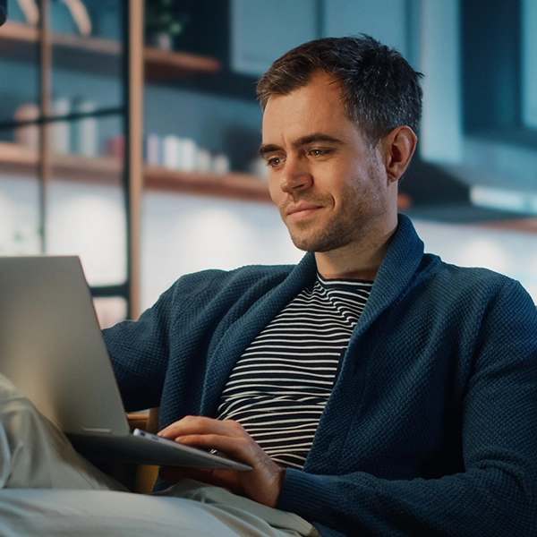 425765993 Man sitting at home on his sofa using his laptop.